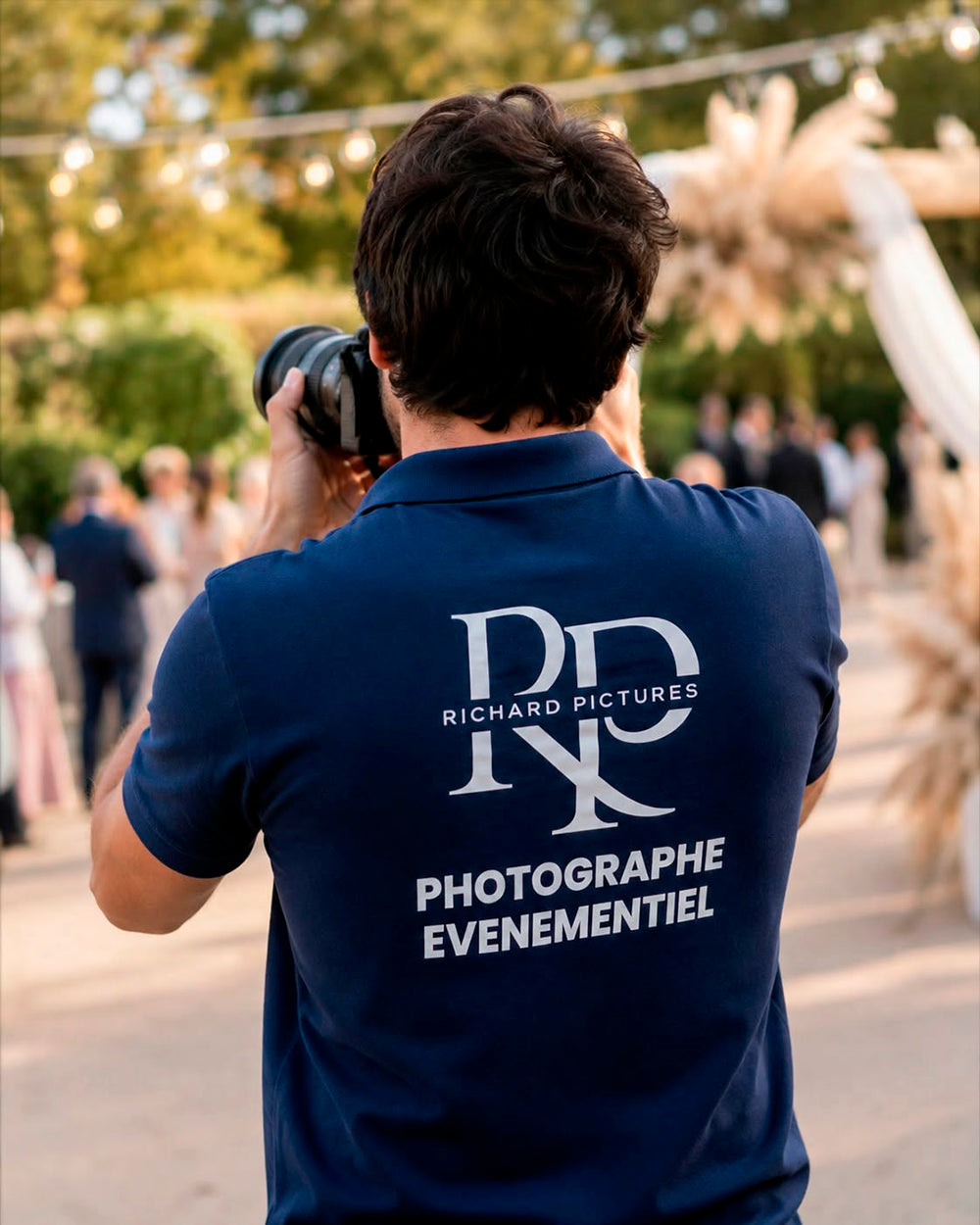 Photographe vu de dos portant un polo bleu marine Richard Pictures Photographie événementielle